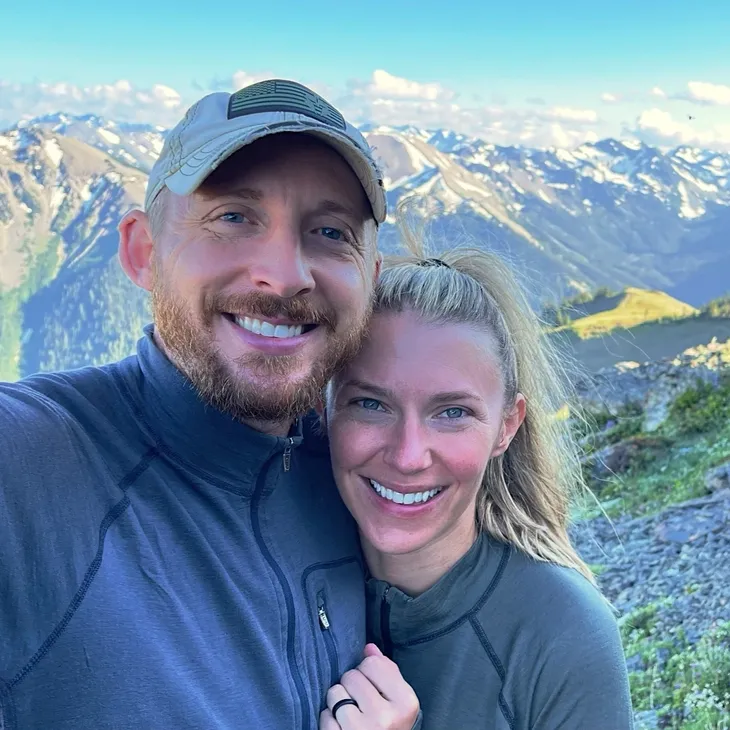 Couple smiling with mountain landscape background.