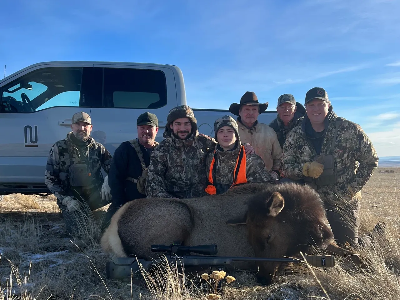 Hunters posing with bison in field.