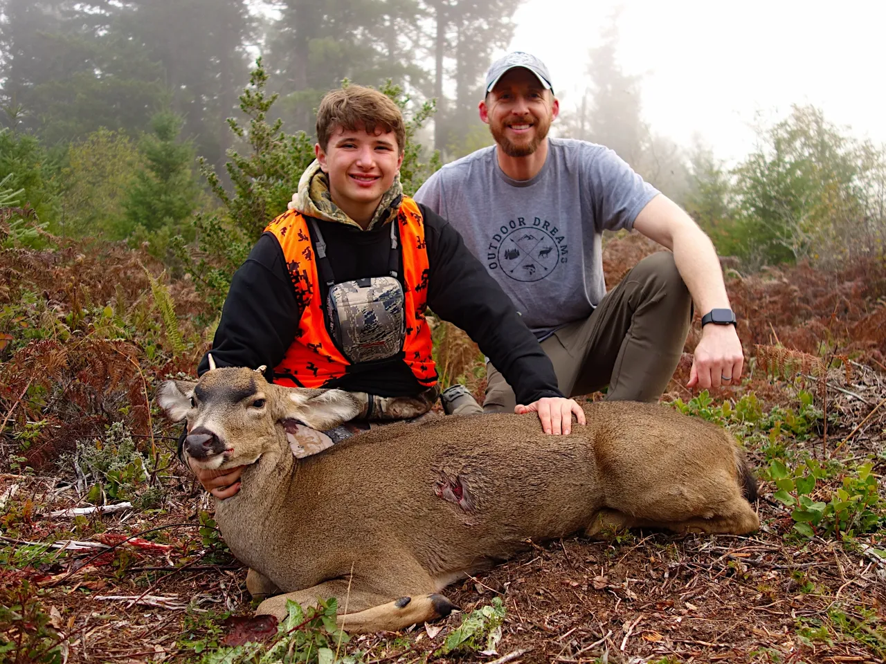 Two hunters posing with a deer.