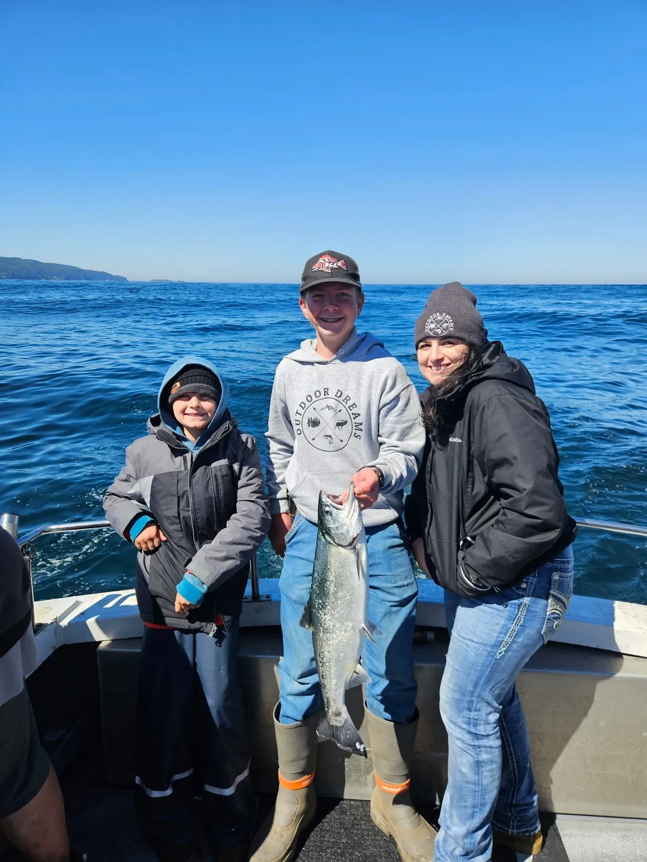 Three people on boat holding a fish.