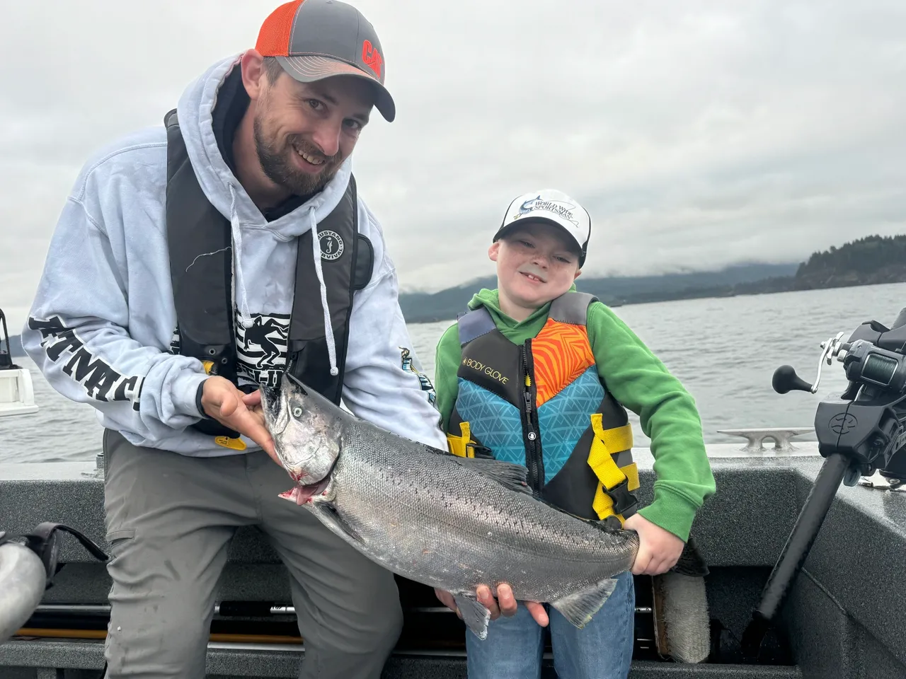 Man and boy holding large fish on boat.