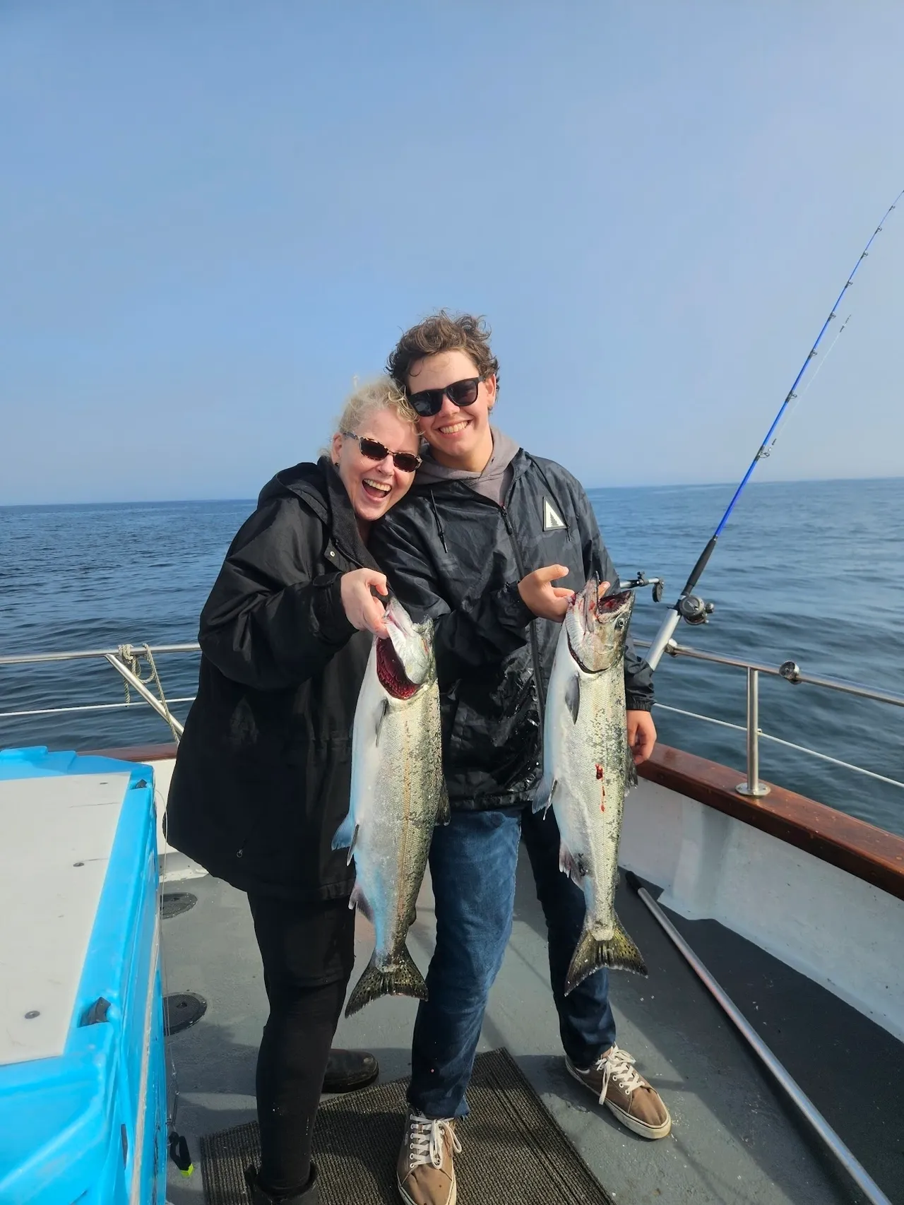 Two people holding fish on a boat.