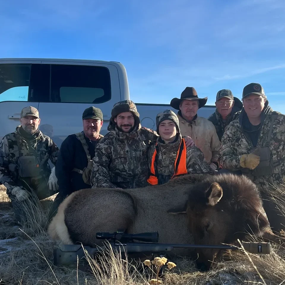 Hunters posing with bison in field.