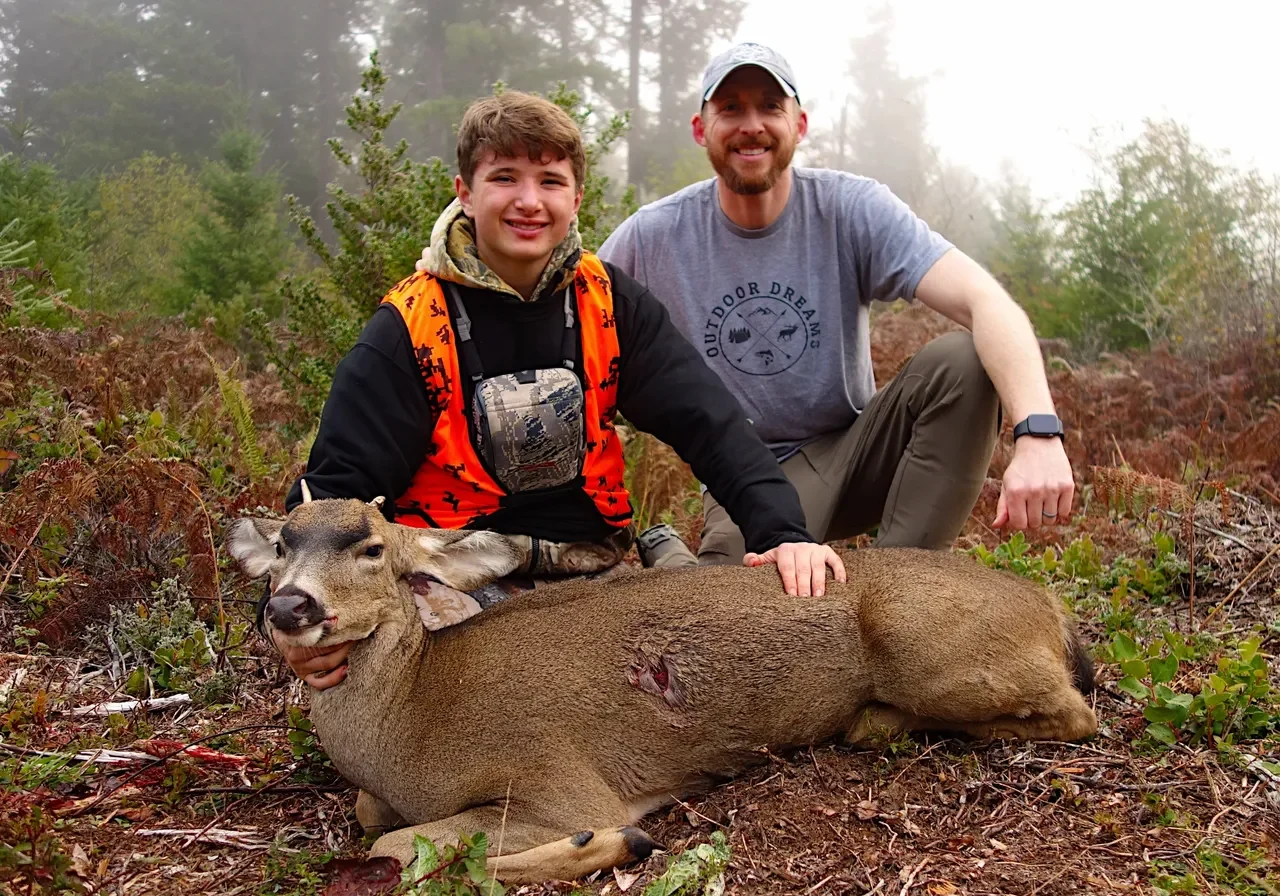 Two hunters posing with a deer.