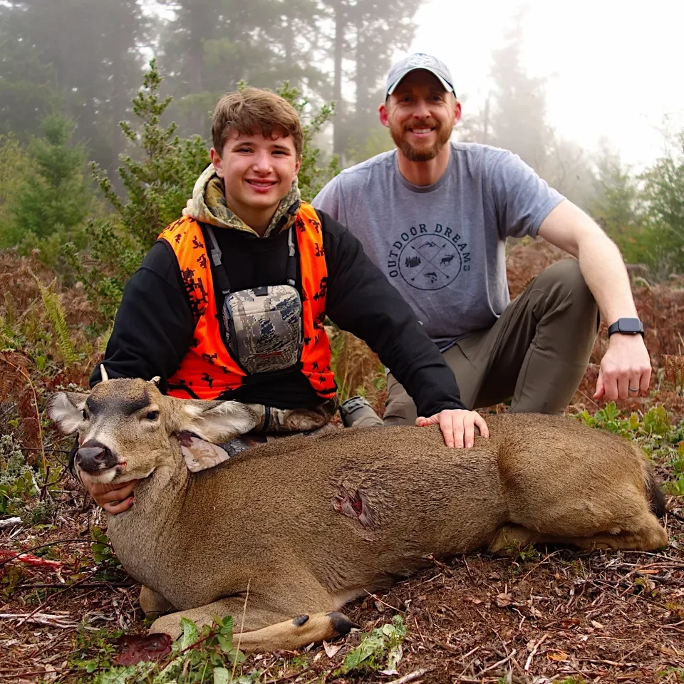 Two hunters posing with a deer.
