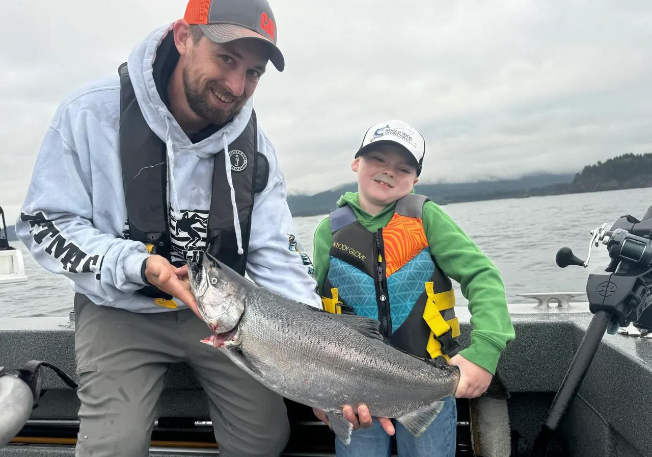 Man and boy holding large fish on boat.