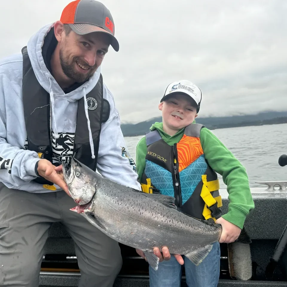 Man and boy holding large fish on boat.