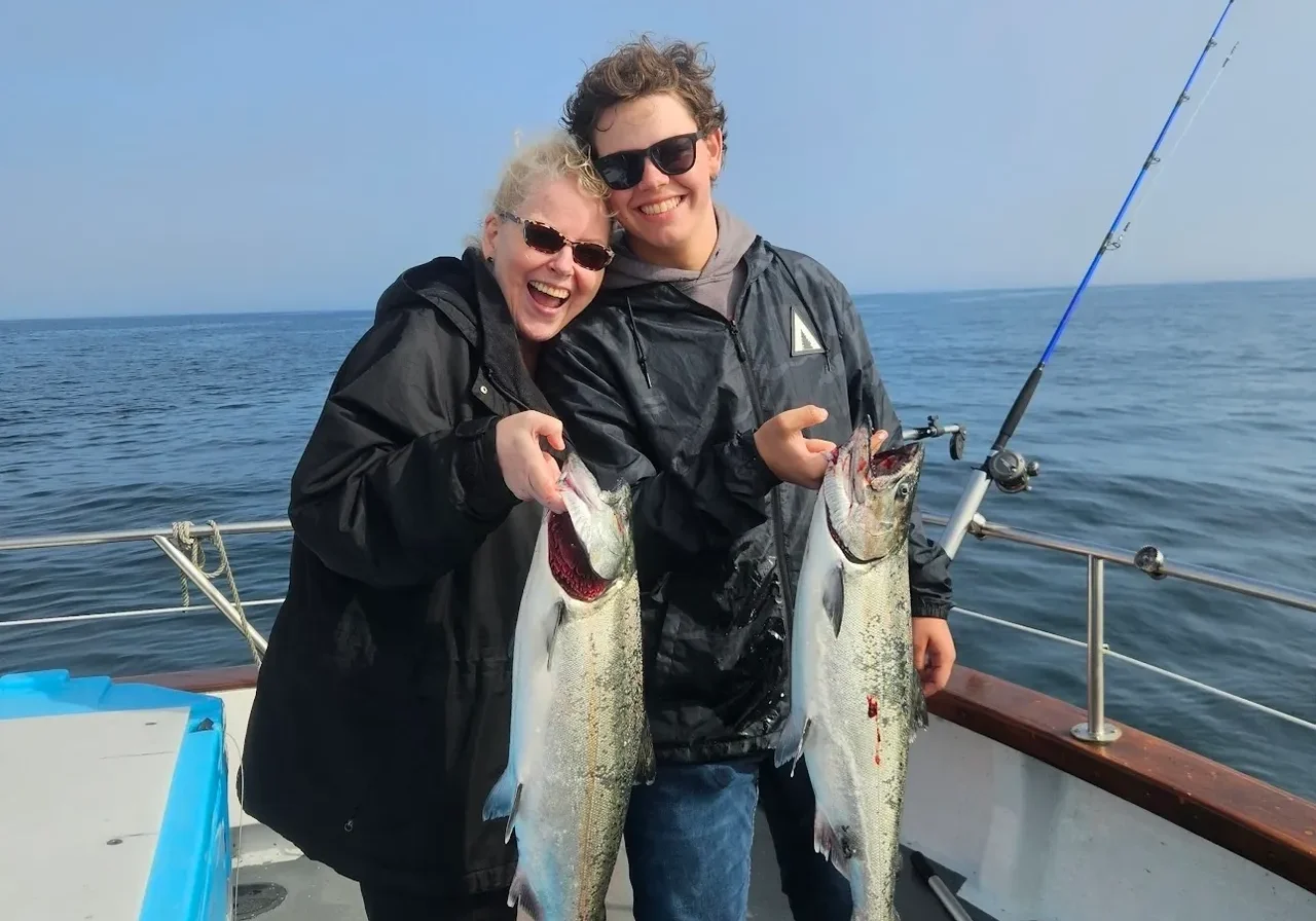 Two people holding fish on a boat.