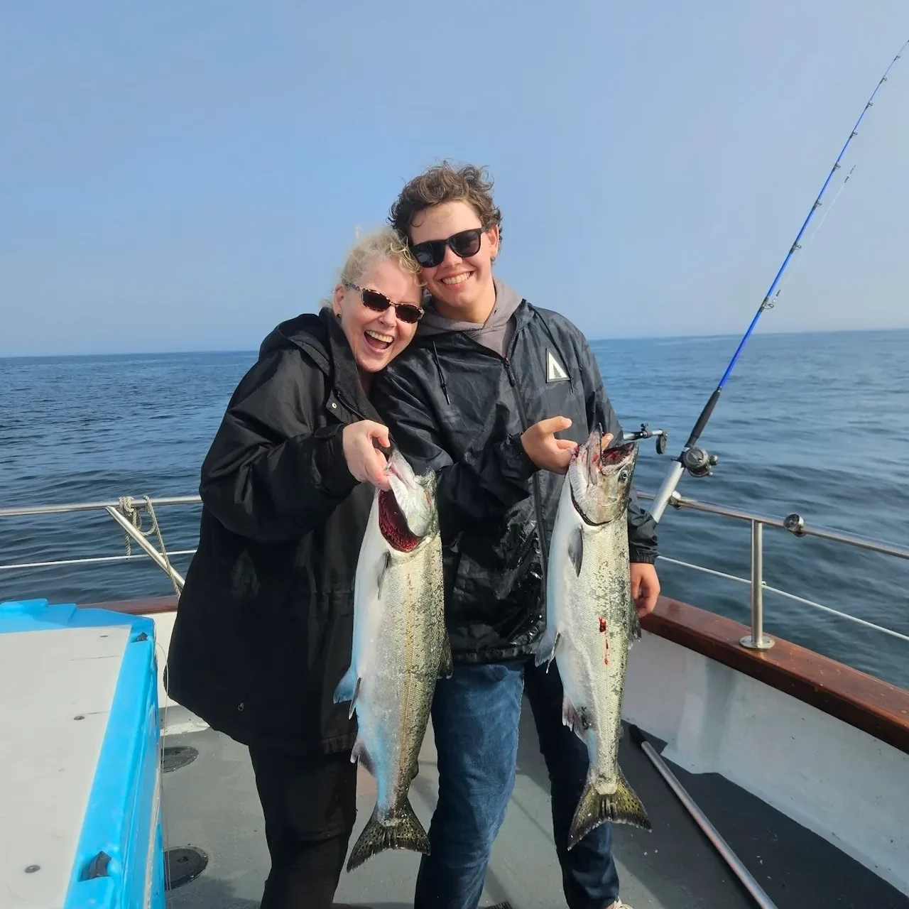 Two people holding fish on a boat.