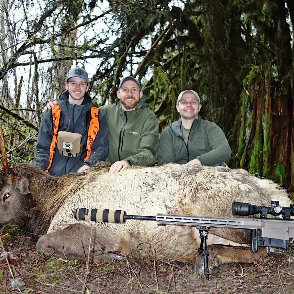 Three hunters posing with harvested elk.